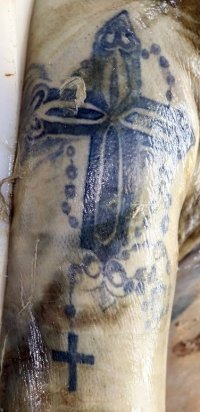 Na zdjęciu widoczna ręka denata, na której znajduje się wytatuowany krzyż.