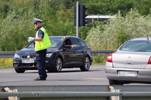 Zdjęcie przedstawia policjanta na skrzyżowaniu podczas regulacji ruchem
