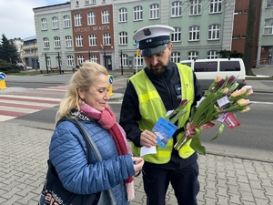 Zdjęcie przedstawia policjanta wręczającego kwiaty paniom.