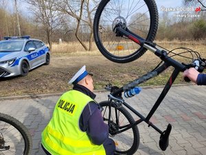 zdjęcie przedstawia policjanta kontrolującego rowerzystę oraz jego rower
